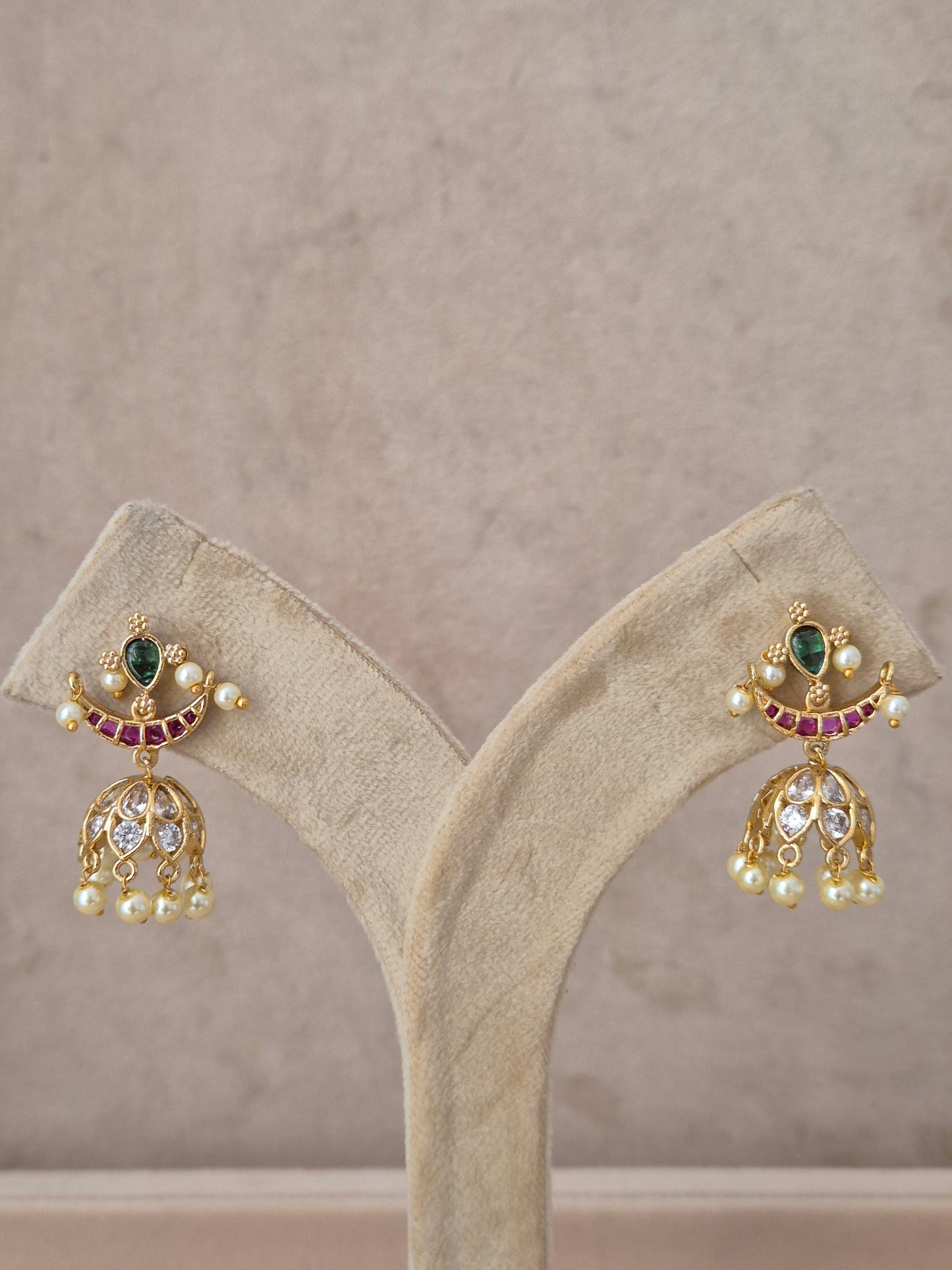 Handcrafted bell-shaped earrings with red and green gemstones and pearl accents from the Naitri Golden Jewellery collection by naitri.in