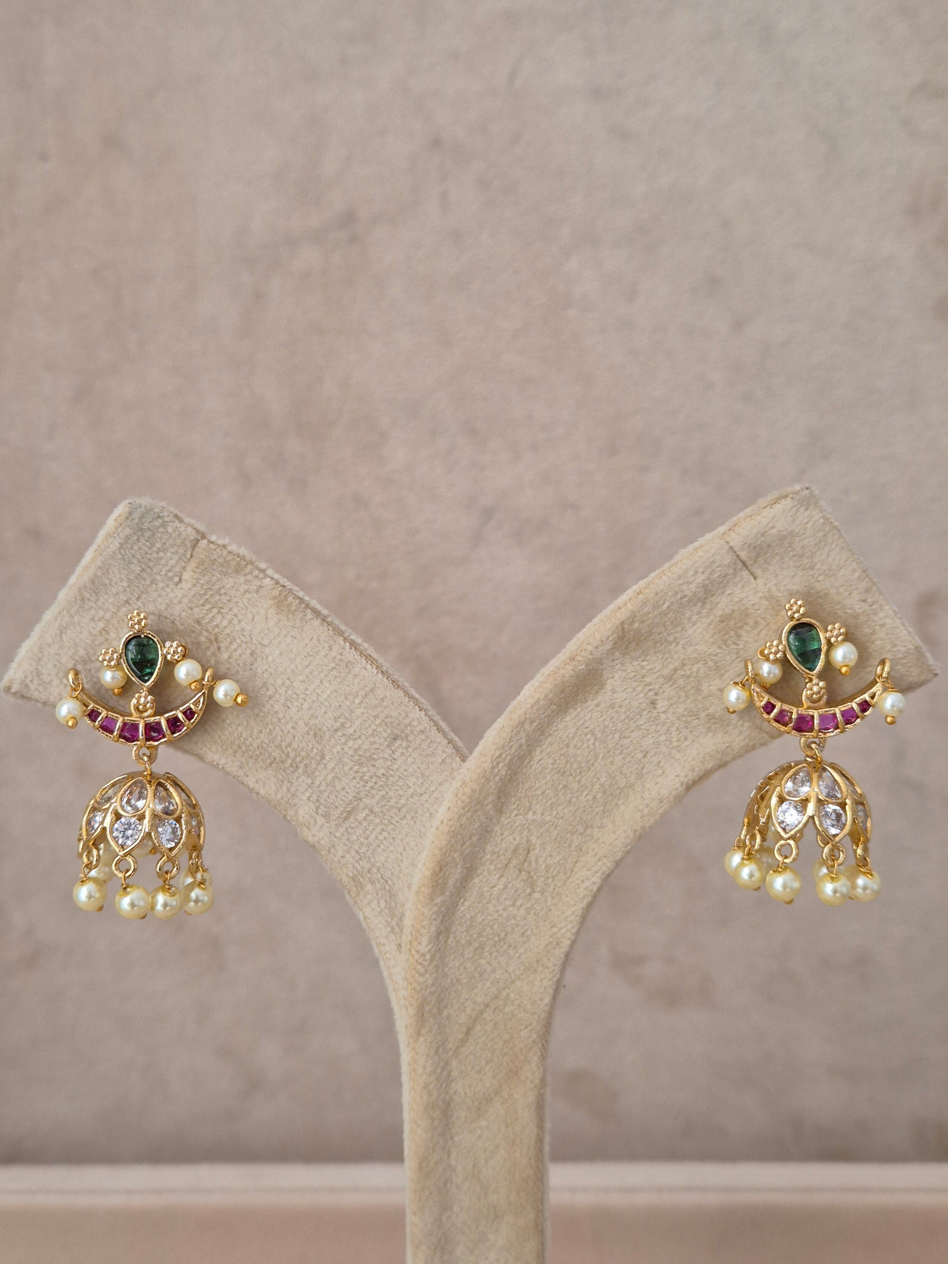 Handcrafted bell-shaped earrings with red and green gemstones and pearl accents from the Naitri Golden Jewellery collection by naitri.in