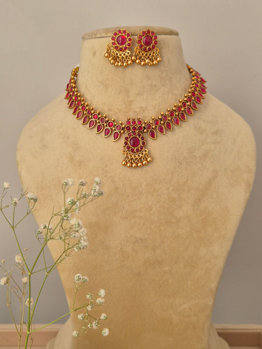 gold-plated choker necklace set with ruby red teardrop stones and matching jhumka-style stud earrings for ethnic wear by naitri.in