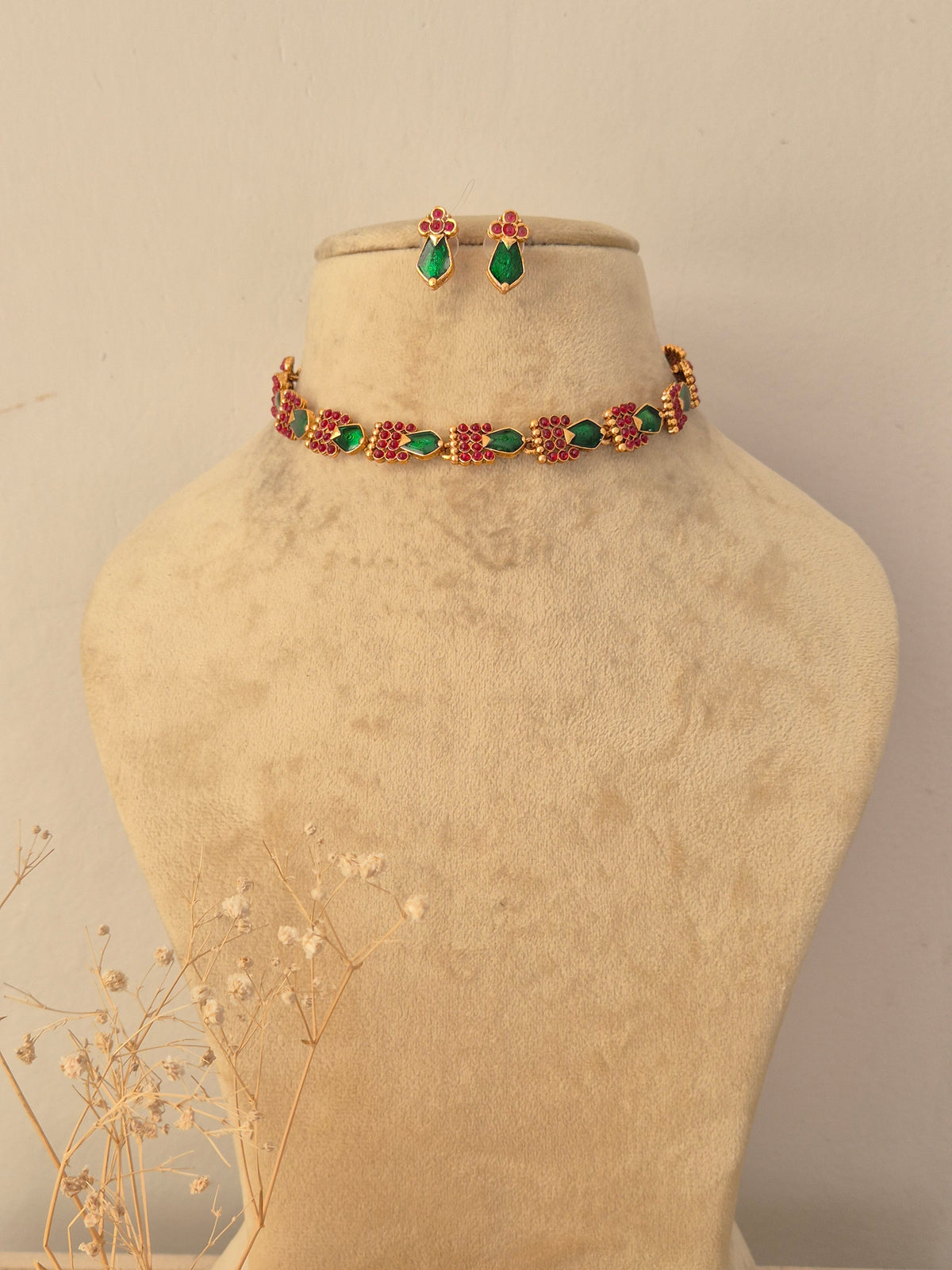 Vasundhara Necklace Set featuring a gold-toned choker with alternating green teardrop stones and pink floral motifs, accompanied by matching teardrop stud earrings by Naitri.in