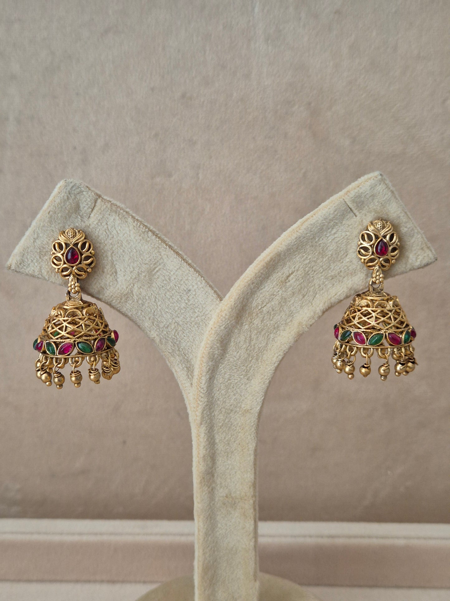 Traditional gold-toned Vedshri Jhumka earrings with red and green gemstone embellishments and dangling gold beads by naitri.in