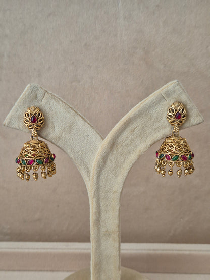 Traditional gold-toned Vedshri Jhumka earrings with red and green gemstone embellishments and dangling gold beads by naitri.in