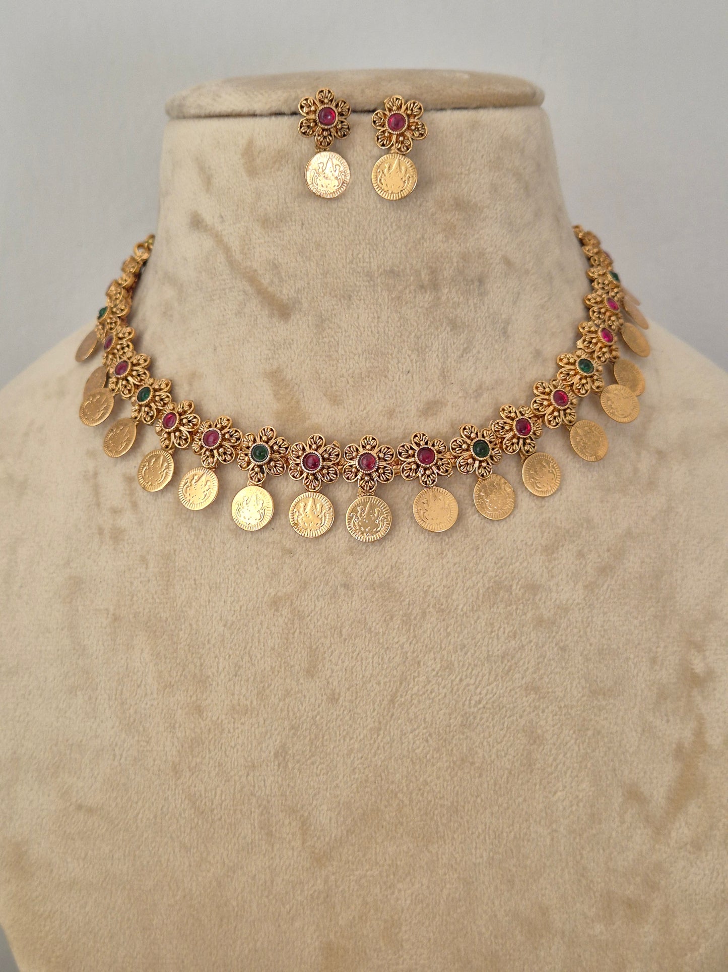 Gold coin necklace and matching earrings the necklace features gold coin-shaped charms interspersed with small red and green stone accents by naitri.in