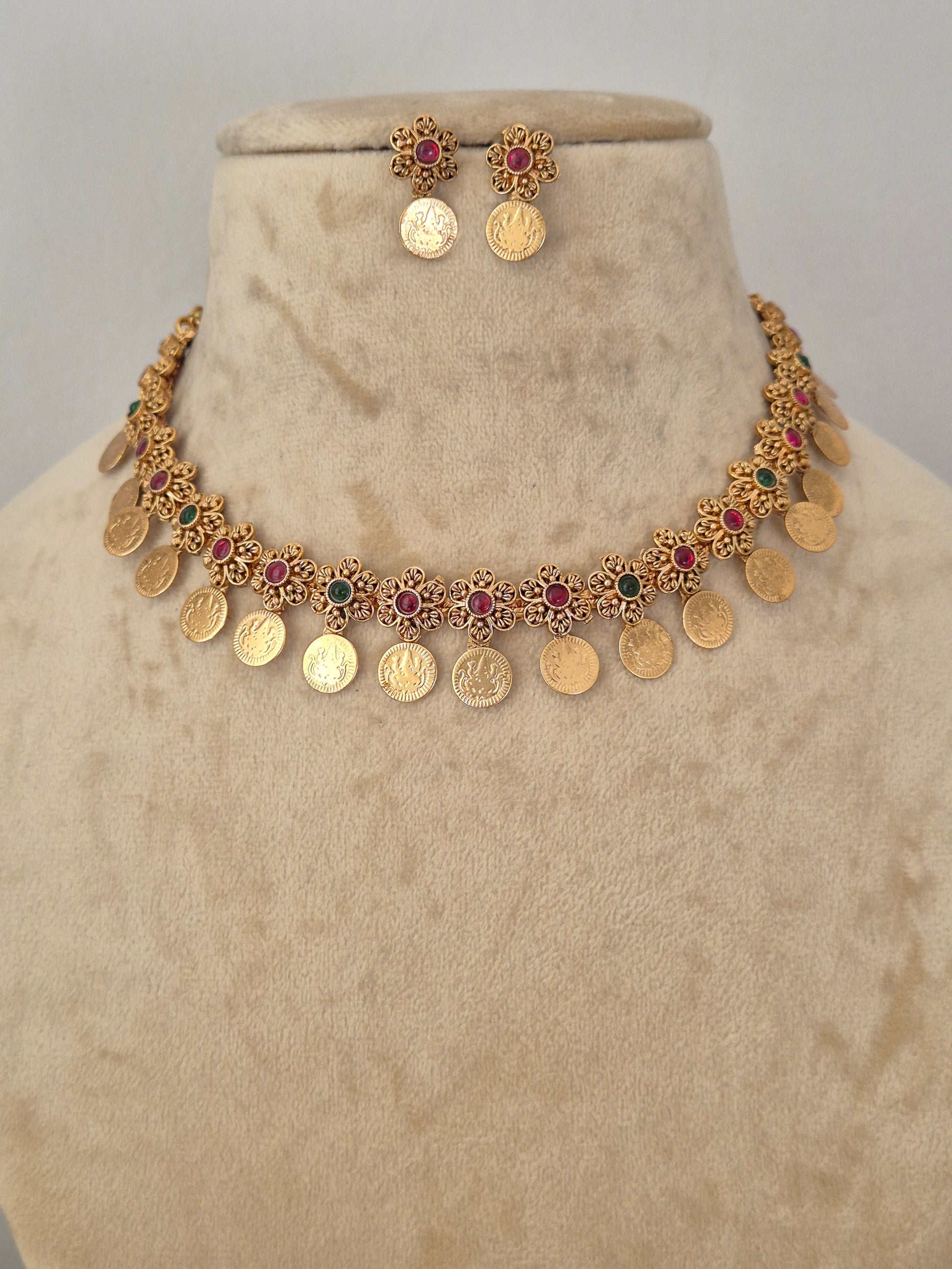 Gold coin necklace and matching earrings the necklace features gold coin-shaped charms interspersed with small red and green stone accents by naitri.in