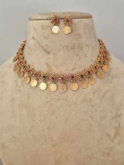 Gold coin necklace and matching earrings the necklace features gold coin-shaped charms interspersed with small red and green stone accents by naitri.in