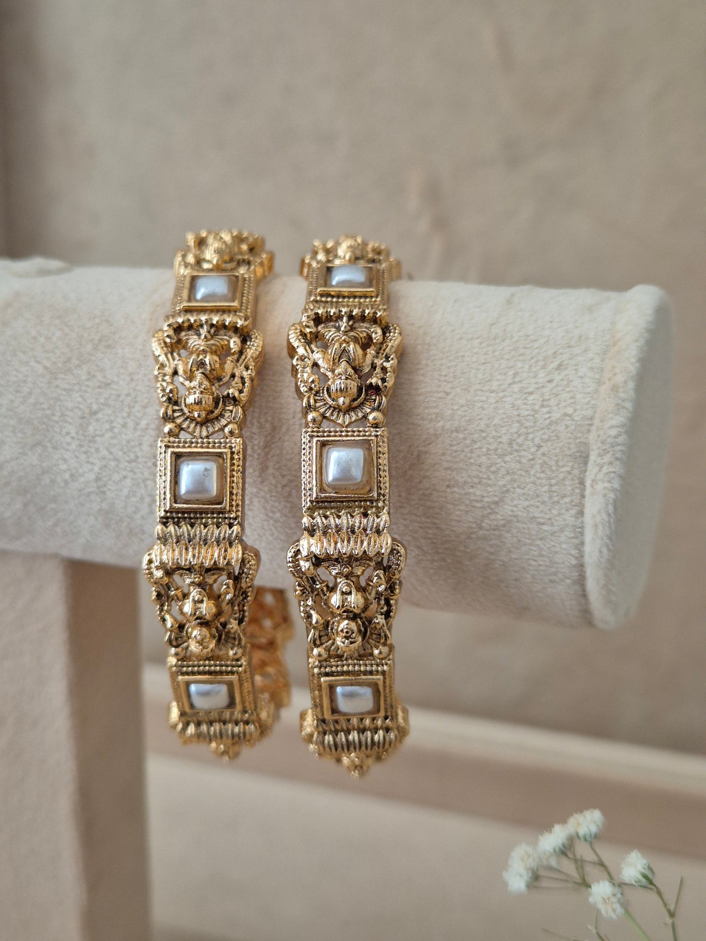 Two traditional gold-plated ethnic bangles with detailed textured patterns and inlaid square white stones By naitri.in