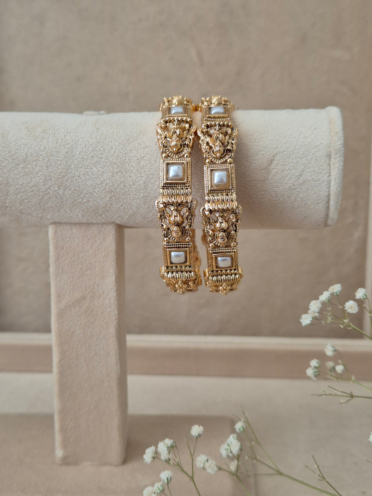 Set of 2 Visha gold bangles by Naitri featuring intricate traditional filigree engravings, accented with square-framed white pearls, by naitri.in