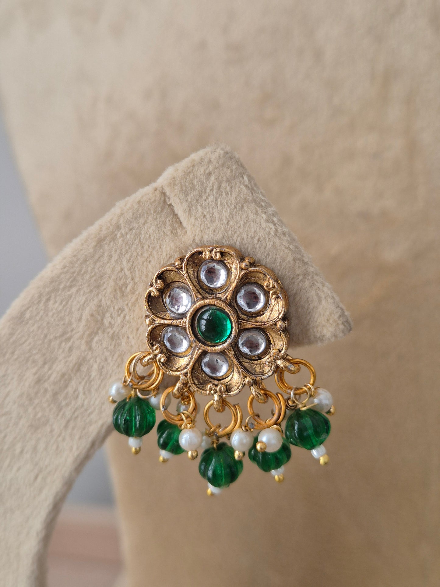 Indian ethnic earrings a prominent gold flower pendant set with white crystals and emerald-green stones, complete with hanging pearls by naitri.in