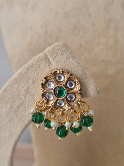 Indian ethnic earrings a prominent gold flower pendant set with white crystals and emerald-green stones, complete with hanging pearls by naitri.in