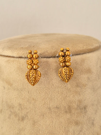 A pair of gold-toned dangle earrings with textured floral and leaf motifs, by naitri.in