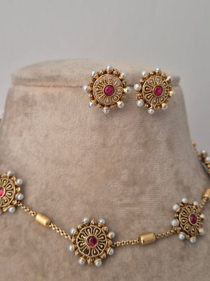 Ornate gold necklace with red stones and pearl-like beads all side of the round flower  pearls unique and minimal designed earring and pendant having same design by naitri.in