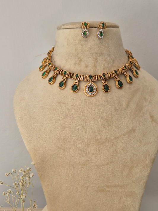 Gold-toned traditional Indian choker necklace and matching oval drop earrings, choker features detailed metallic motifs set with alternating teardrop-shaped green gemstone drops, by naitri.in