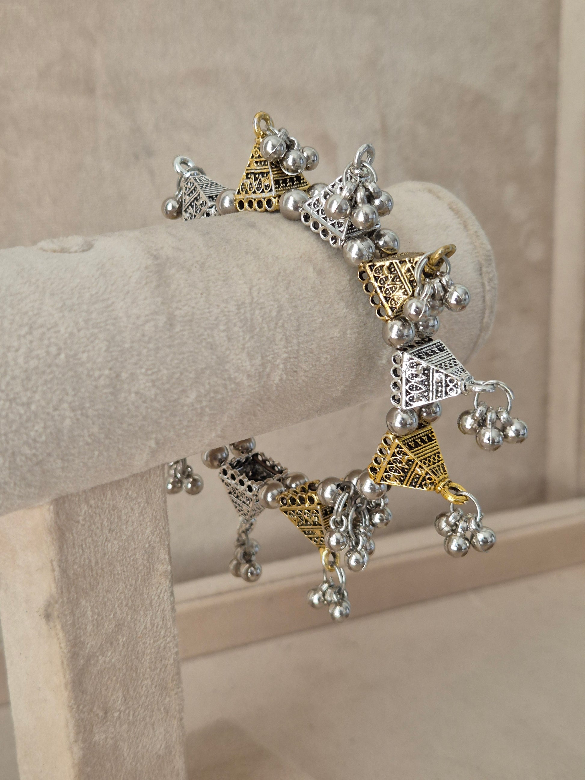 Dual-toned gold and silver Yachana bangle with textured geometric blocks and hanging silver ghungroo charms. Elegant dual-tone ethnic cuff bracelet with traditional festive details, by naitri.in
