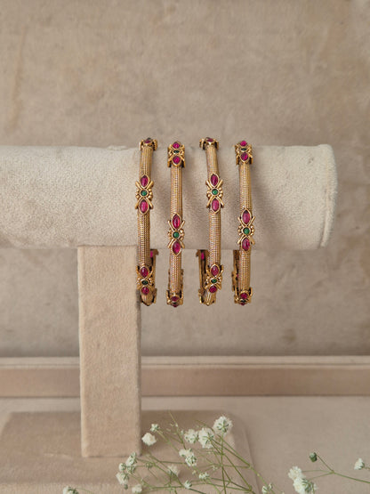 set of 4 antique gold-plated bangles featuring intricate metalwork and ruby-red and green stone embellishments by naitri.in
