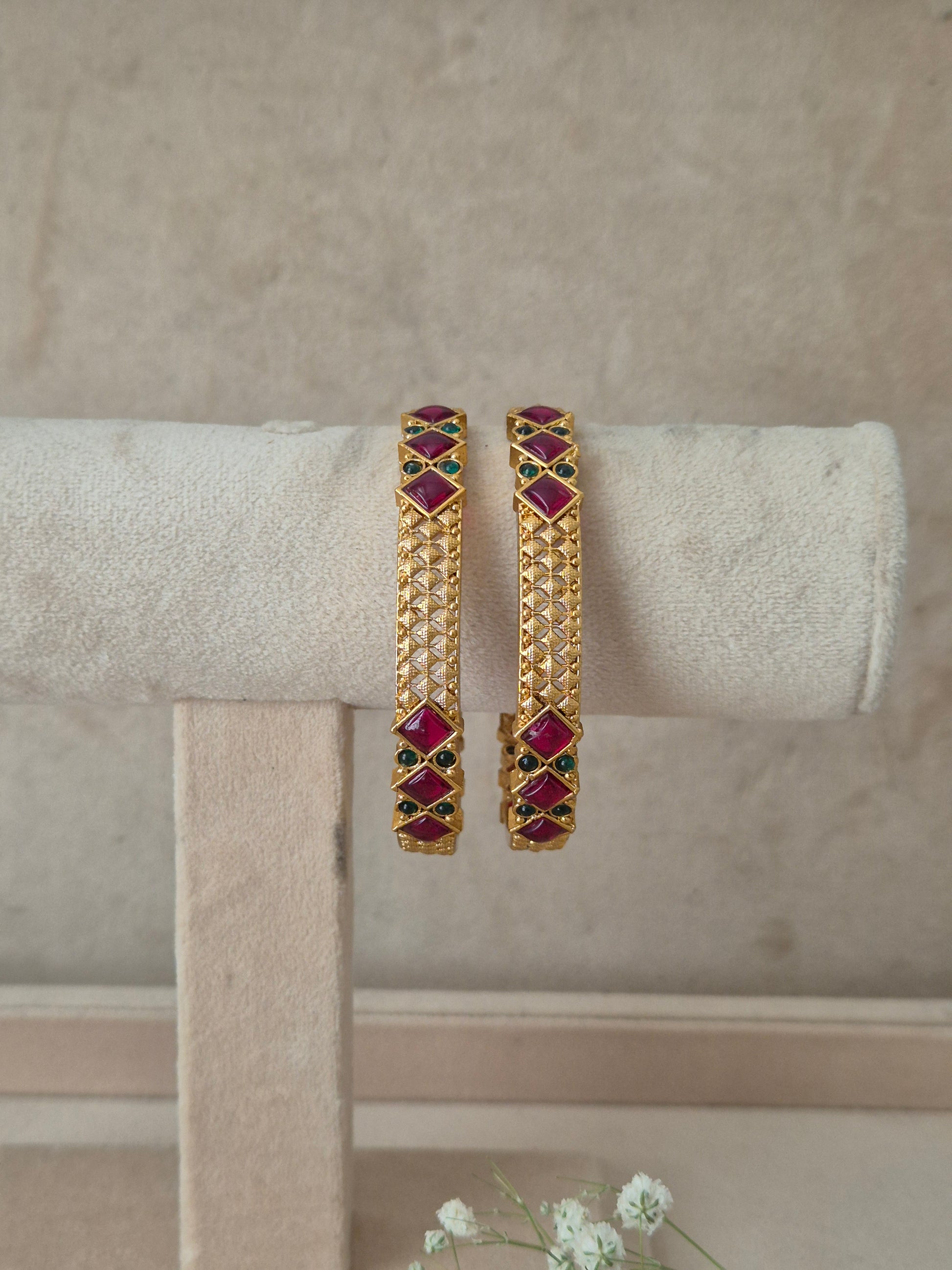A pair of gold-plated bangles decorated with red and green stones, by naitri.in