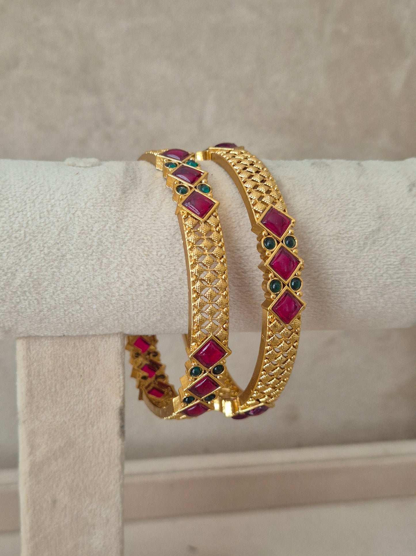 Gold-plated bangle bracelet with red and green stone accents, by naitri.in
