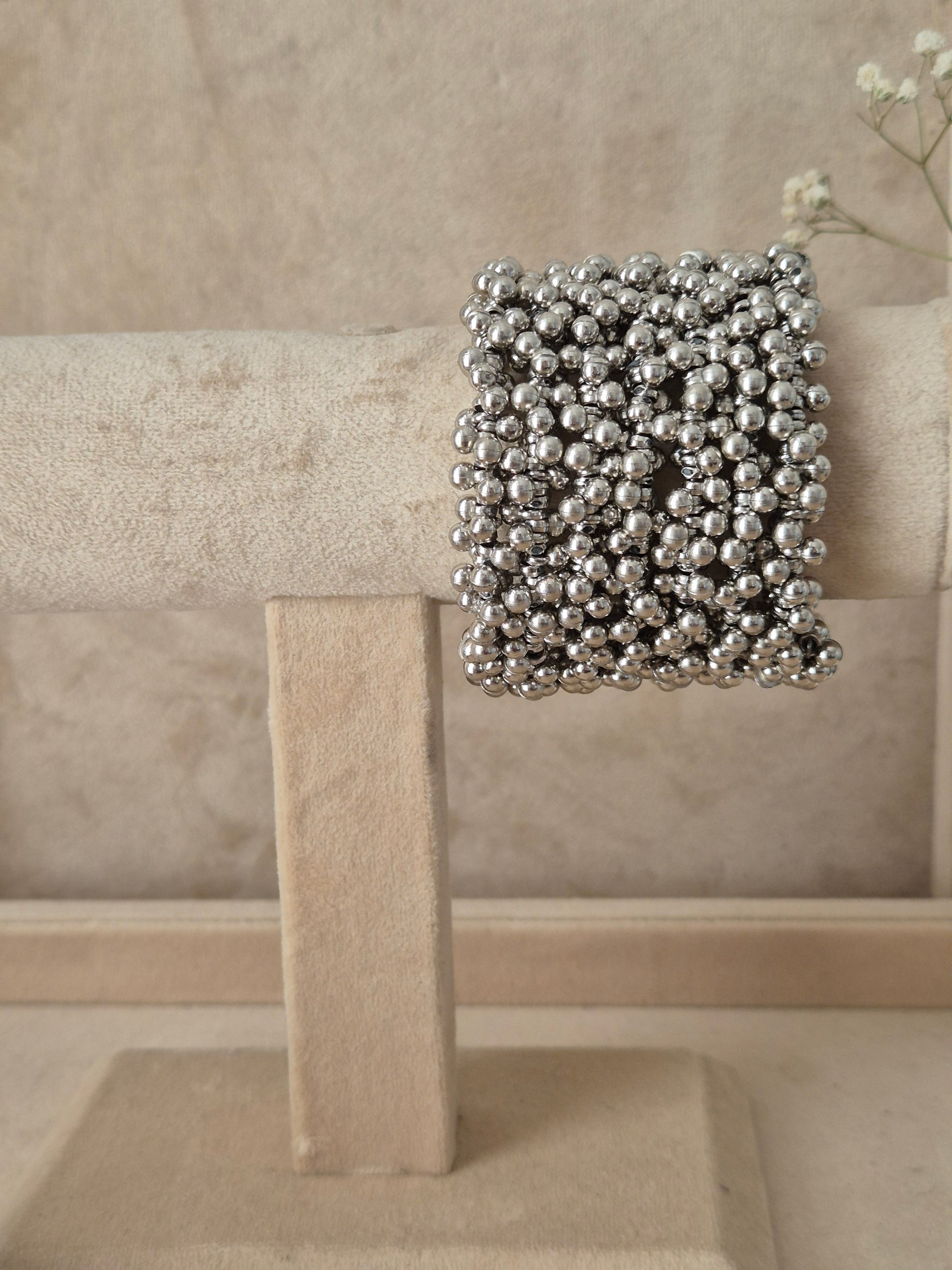Modern silver spiral bangle bracelet covered in small metallic beads by naitri.in