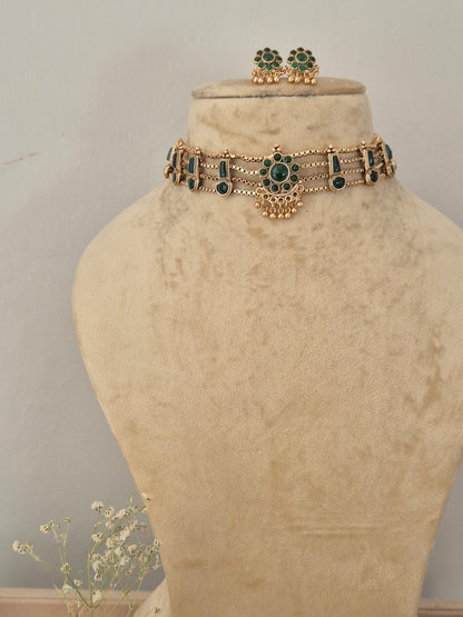 Gold-plated ethnic choker necklace featuring emerald-green gemstone accents and matching hanging stud earrings, by naitri.in