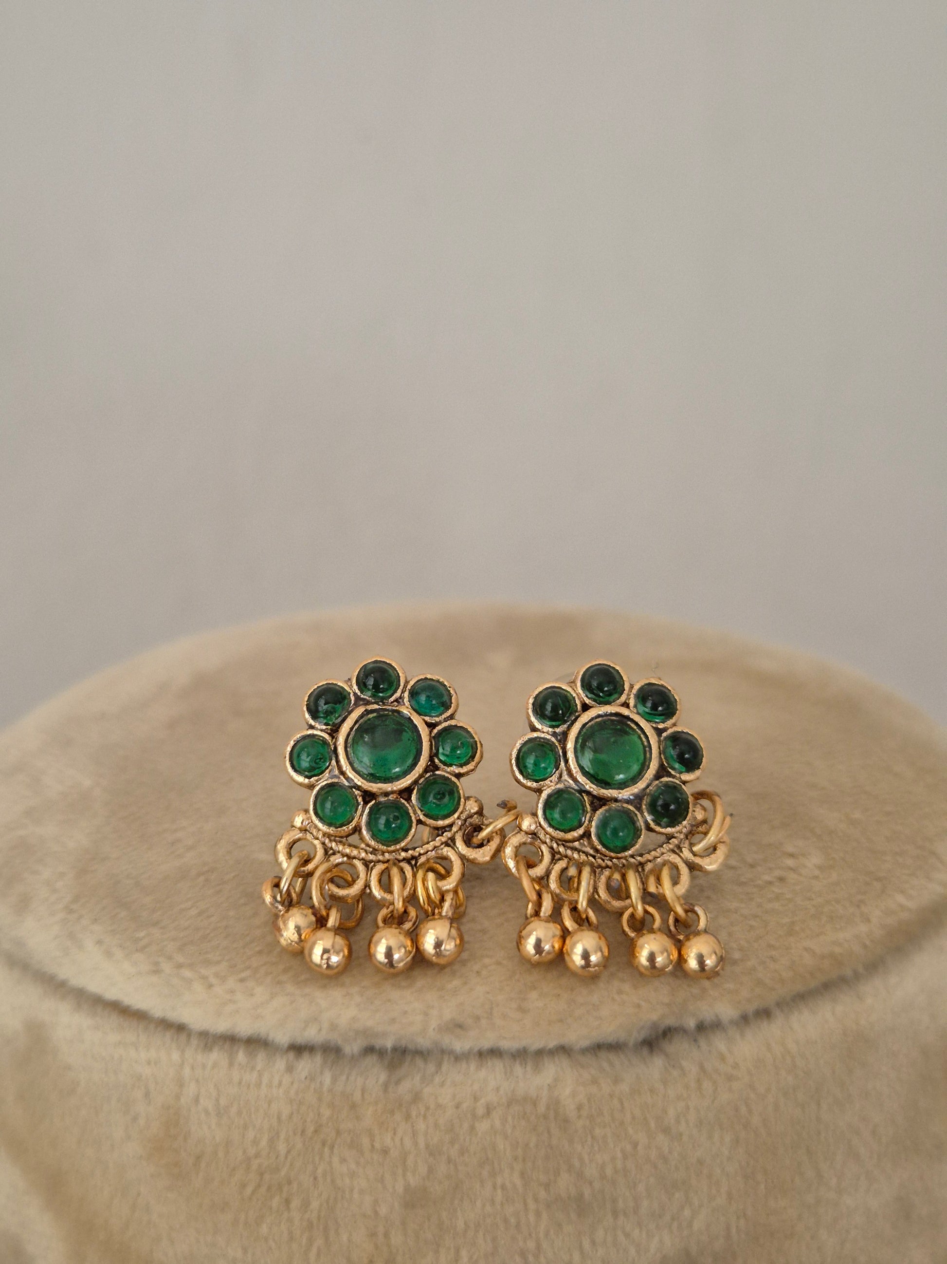 Antique gold-toned earrings intricate metallic round floral vibrant green stone clusters, and delicate hanging gold bead drops by naitri.in
