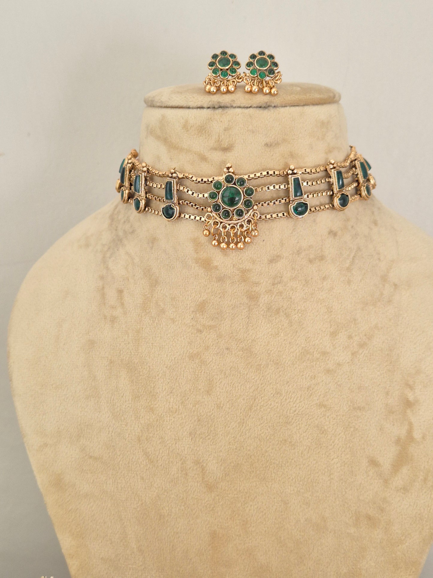 Handcrafted antique gold statement jewelry set decorated with intricate traditional patterns and green gemstone details, ideal for festive or wedding wear by naitri.in