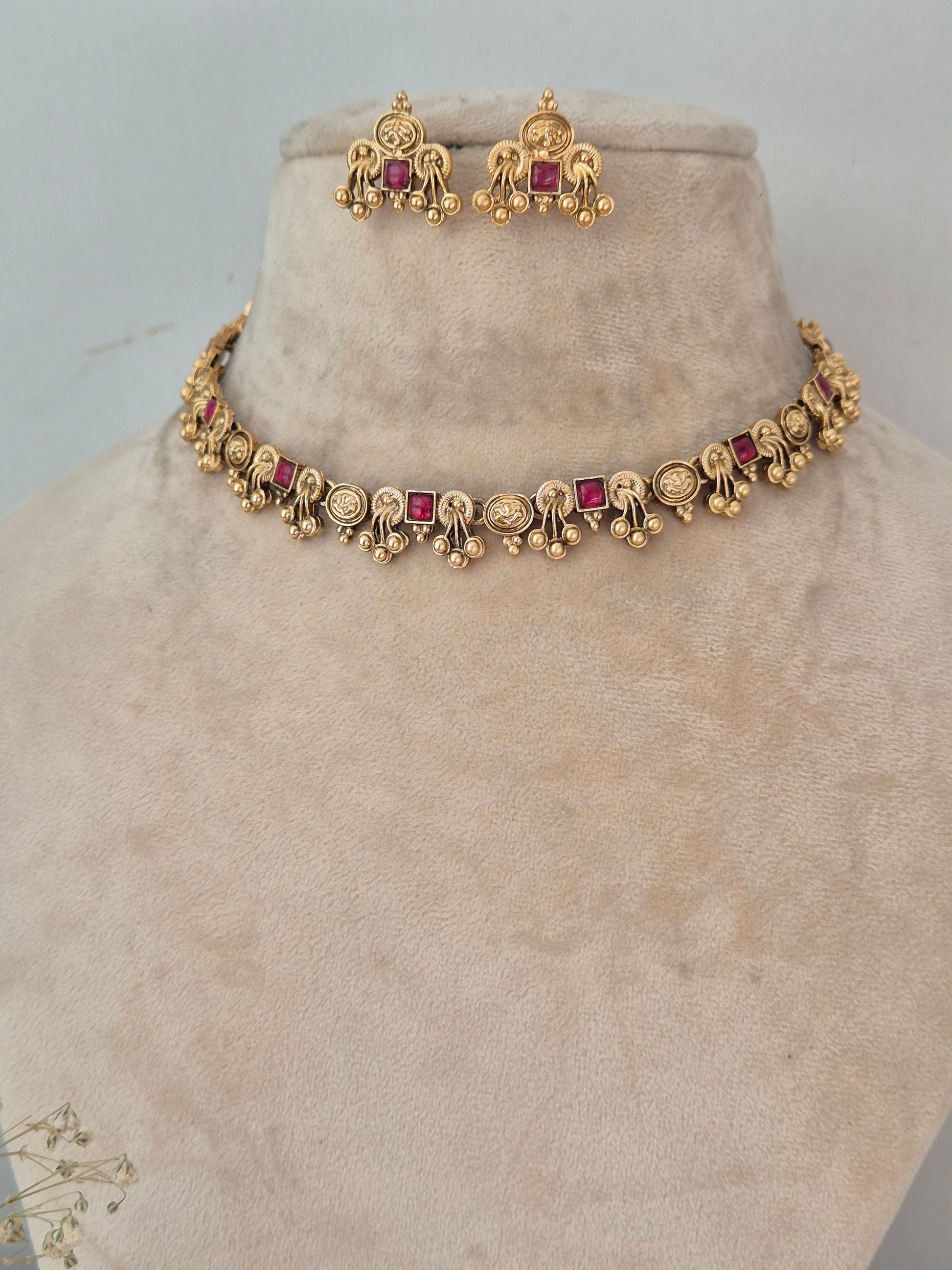 Gold-toned traditional Indian jewelry set featuring a bracelet and matching earrings with small red square gemstones, by naitri.in