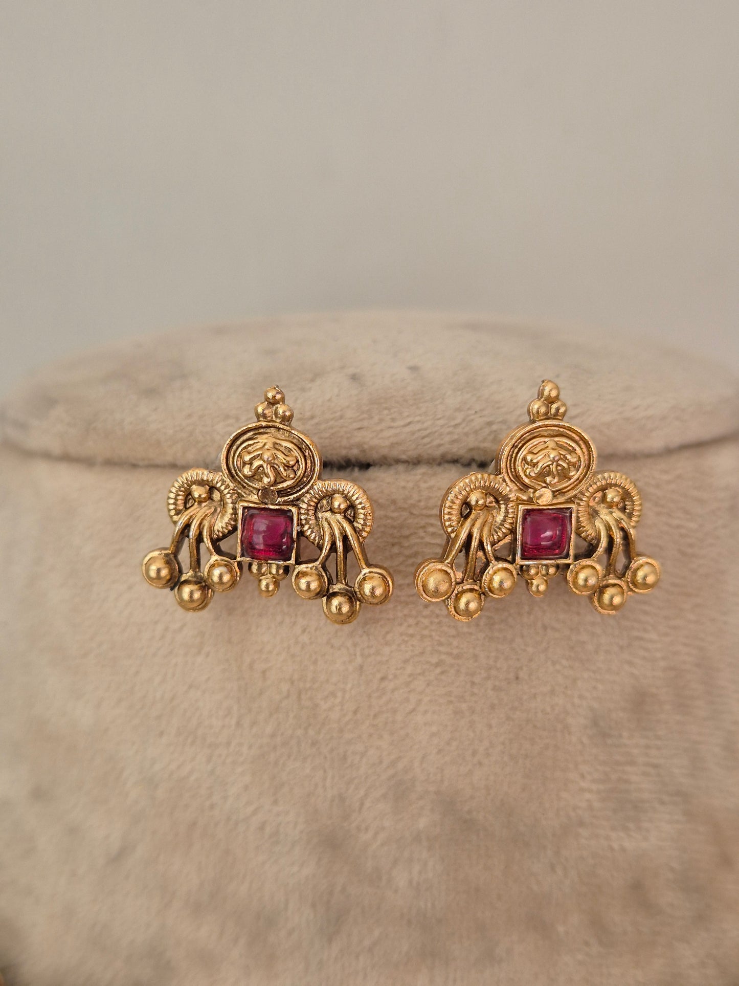 A pair of ornate gold earrings with square pink gemstones, by naitri.in