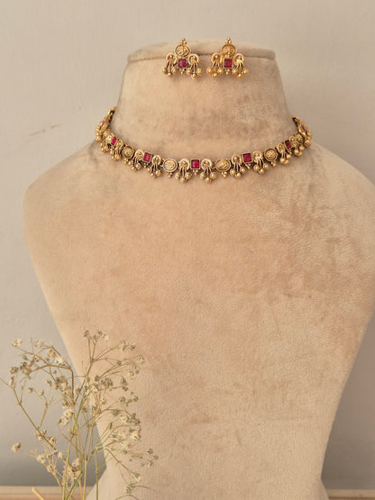 Gold-toned traditional Indian jewelry set featuring a necklace with red stones and matching earrings, by naitri.in