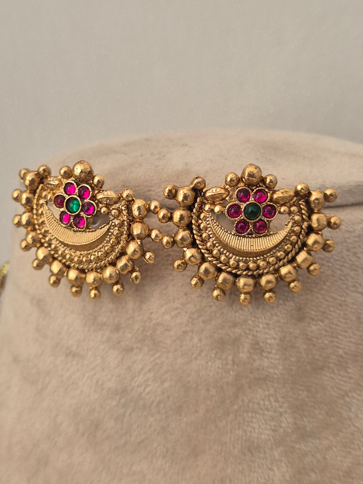 Antique gold earrings with a semicircular pendant featuring pink stone accents, and beaded trim by naitri.in