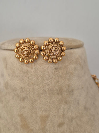 A close-up of ornate gold-toned detailed and circular earrings by naitri.in
