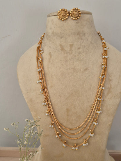 A gold-toned multi-strand chain necklace with small white pearl-like beads, a matching gold-toned circular pendant by naitri.in