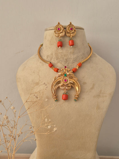 Kishori Necklace Set in antique gold finish featuring a statement pendant and matching drop earrings on a mannequin by Naitri.in